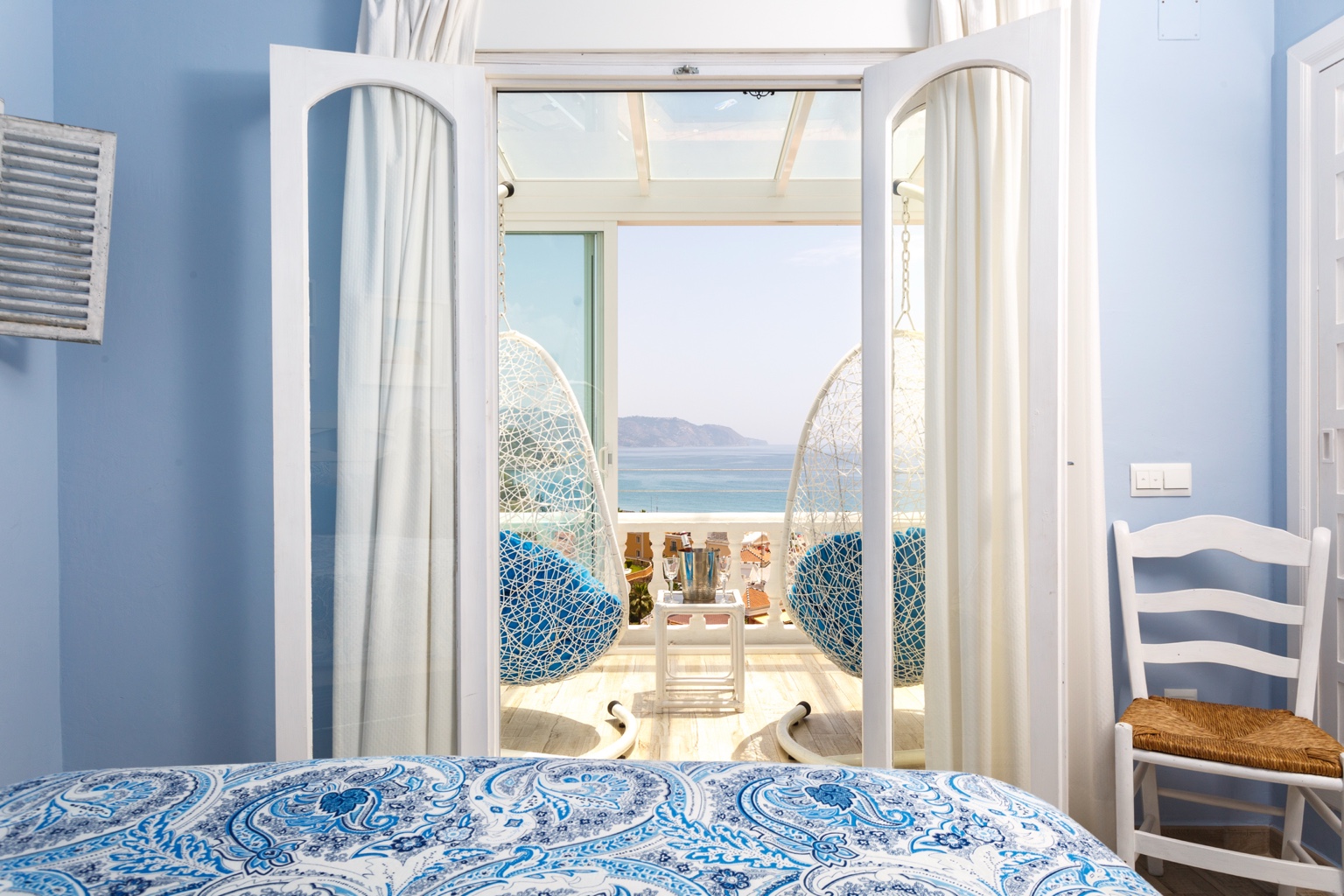 Blue bedroom opening to sea-view balcony